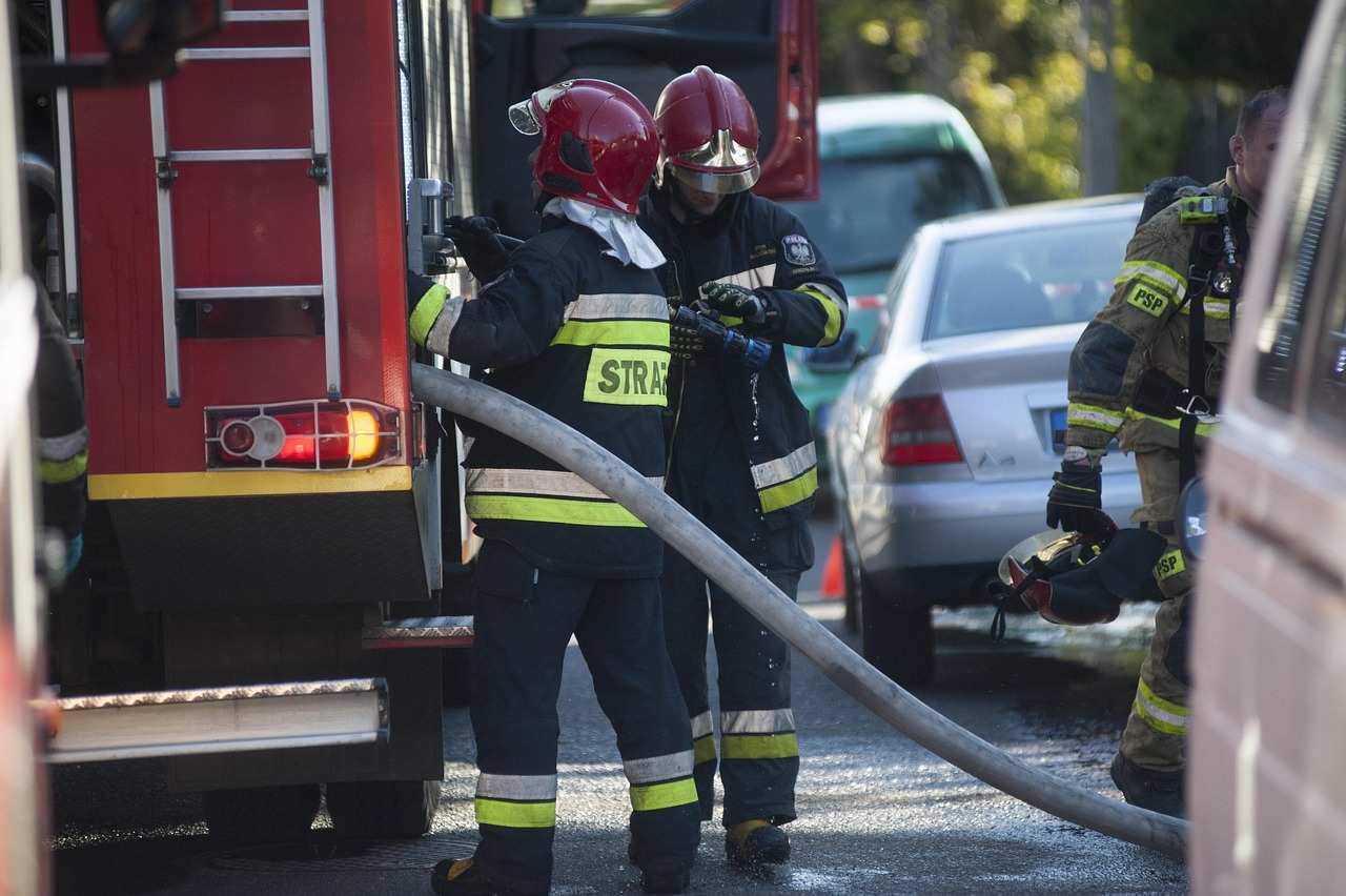 Firefighters connecting hose to fire truck during emergency response, demonstrating practical skills learned through safety certification courses