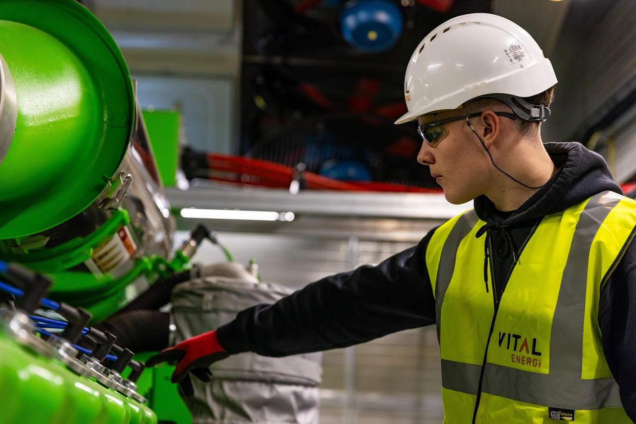 Engineer in safety vest and helmet operating machinery, highlighting the importance of hands-on safety certification courses in industrial environments
